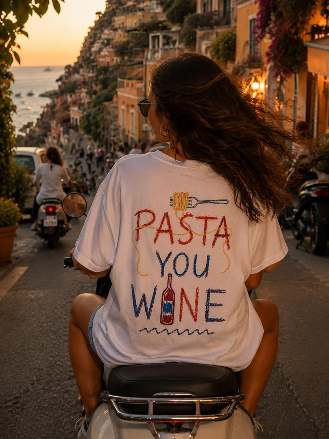 A woman riding a Vespa down a coastal hillside at sunset